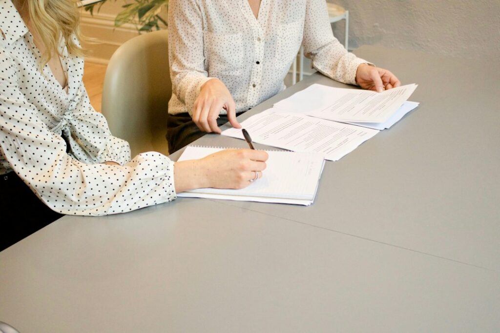 Job seeker reviews employment paperwork with a staffing coordinator at a desk.