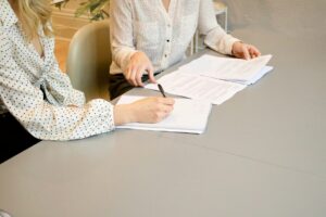 Job seeker reviews employment paperwork with a staffing coordinator at a desk.