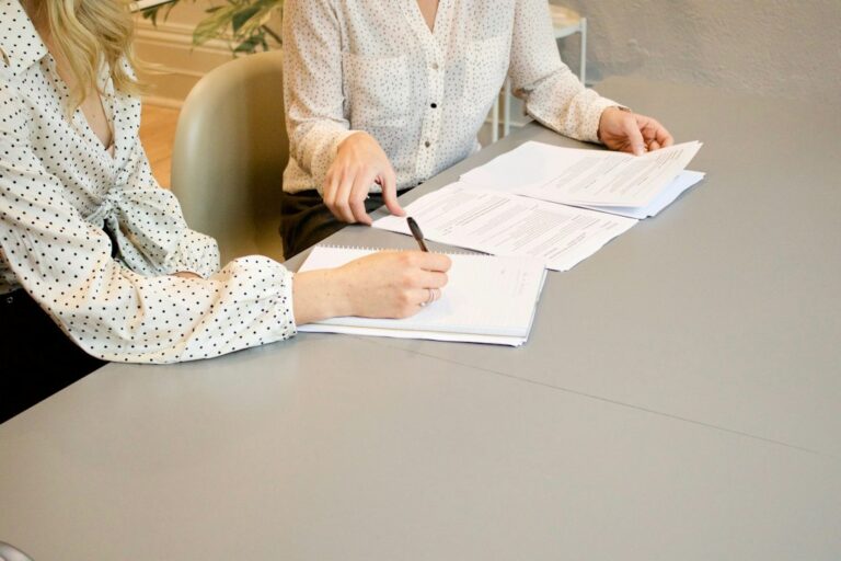 Job seeker reviews employment paperwork with a staffing coordinator at a desk.